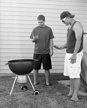 Due ragazzi guardano il proprio smartphone davanti a un BBQ, ma lo smartphone è stato rimosso dalla foto.